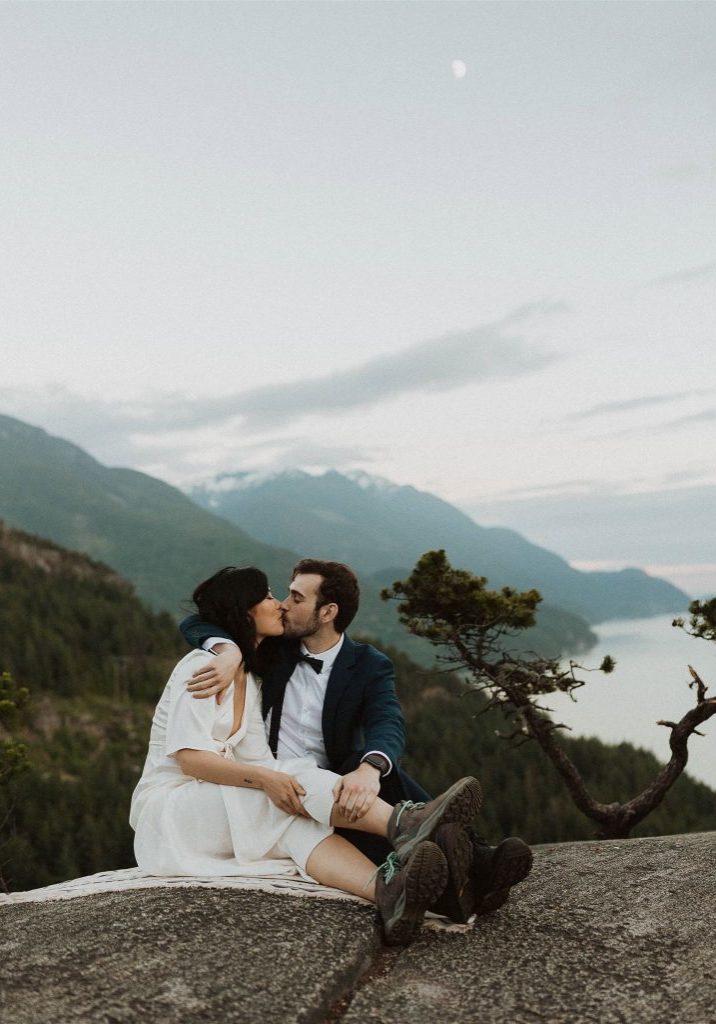 Eloping couple kissing at mountain peak in Squamish.