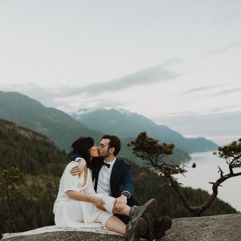 Eloping couple kissing at mountain peak in Squamish.